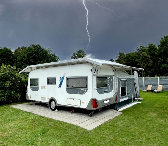 Gewitter mit Blitz über einem Wohnwagen auf dem Campingplatz