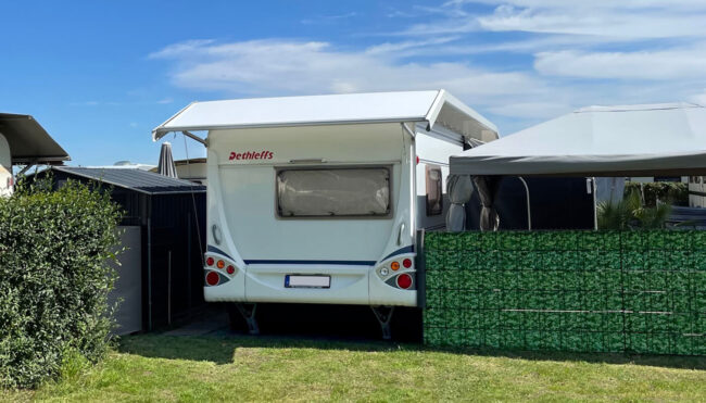 Wohnwagen mit Schutzdach auf dem Campingplatz, Frontansicht